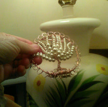 Load image into Gallery viewer, Pearl TOL being held n hand, in front of a lamp which has a floral  designdesgn
