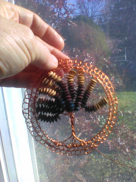 Beaded Copper Wire Tree of Life Kippah being held in front of a window