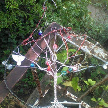 Load image into Gallery viewer, Akedah Wall hanging or Suncatcher on a railing with green vines in background