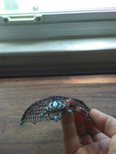 Load image into Gallery viewer, Black wire kippah with turqoise beads and fleur-de-lis-charm , shown  being held