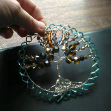 Load image into Gallery viewer, Silver, amber, copper and blue Tree of Life wall hanging being held on a black and brown background