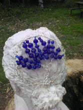 Load image into Gallery viewer, A silver and blue tree of life kippah on the bust of a woman's head. A tree trunk is visible in the foreground and there is an angel sculpture in the garden.