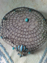 Load image into Gallery viewer, Black wire kippah   with turquoise beading and fleur-de-lis charm on a blue and white  embroidered tablecloth