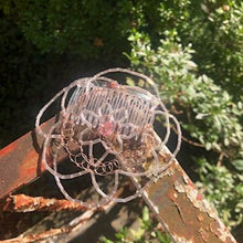 Load image into Gallery viewer, Beaded wire kippah inspired by flowers, shown on vintage railing with greenery in background

