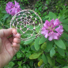 Load image into Gallery viewer, Picture shows a beaded rose gold wre kppah beng held against a background of rhododendron flowers and green leaves
