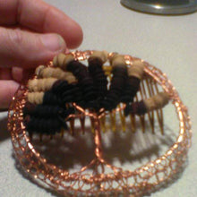 Load image into Gallery viewer, Copper wire  Tree of Life kippah with repurposed wooden beads and comb. The kippah is being held against a grey background and there is a contaner in the upper right corner (not included)
