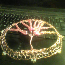 Load image into Gallery viewer, Pink and gold-pink crystals and glass beads are the leaves of the Tee of Life kippah, while the tree itself and the wire circles which support it are rose gold. The kppah rests on a laptop.
