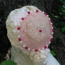 Load image into Gallery viewer, Rose gold wire kippah wih dark pink bead in the middle, and alternating dark and light pink beads and translucent crystals. Displayed on a sculpture, with a tree in the background.
