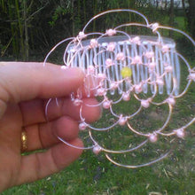 Load image into Gallery viewer, A solitary yellow bead is at the center of the silver wire and pearl kippah, which is being held against a backdrop of trees
