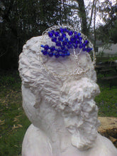 Load image into Gallery viewer, Silver and blue tree of life kippah rests on a bust of a woman. The bust is displayed outside, with a tree trunk, table, and more trees in the background.
