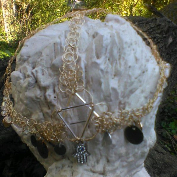 Headdress on statue. Made from gold wire, silver bugle beads in the shape of a Jewish star, coins, and 2 hamsa.s