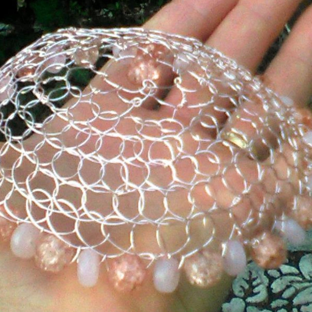 Peach and pink beaded wire kippah being held