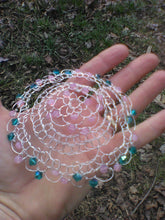 Load image into Gallery viewer, Teal and pink beaded silver wire kippah. The kippah is on a hand to show the size.
